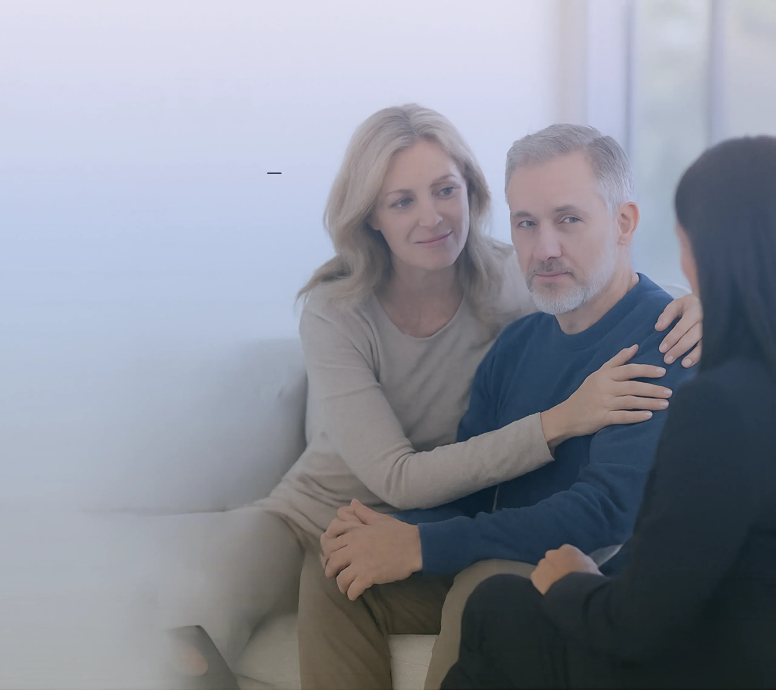 A couple sits with a professional advisor, receiving supportive guidance during a real estate consultation.